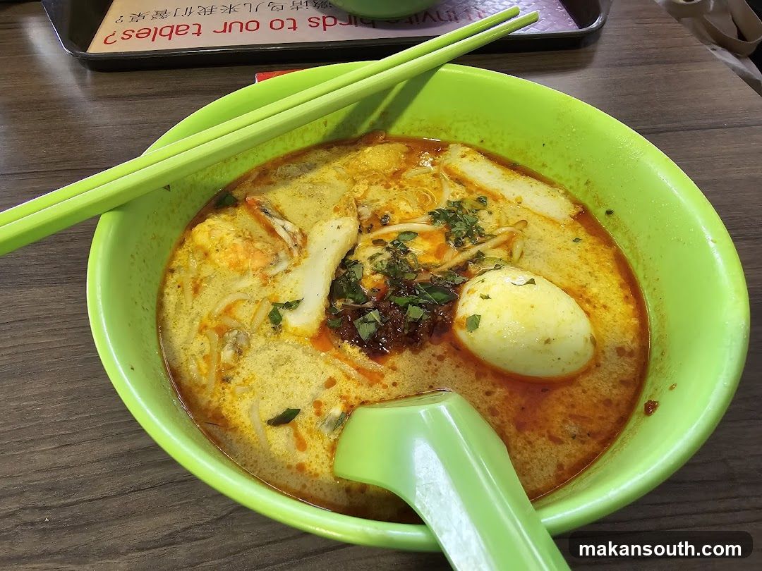 Lime Green Bowl of Spicy Noodle Soup with Halved Egg and Garnishes
