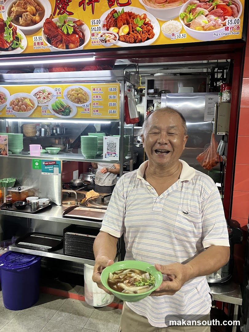 Man holding a bowl of food in front of a stall