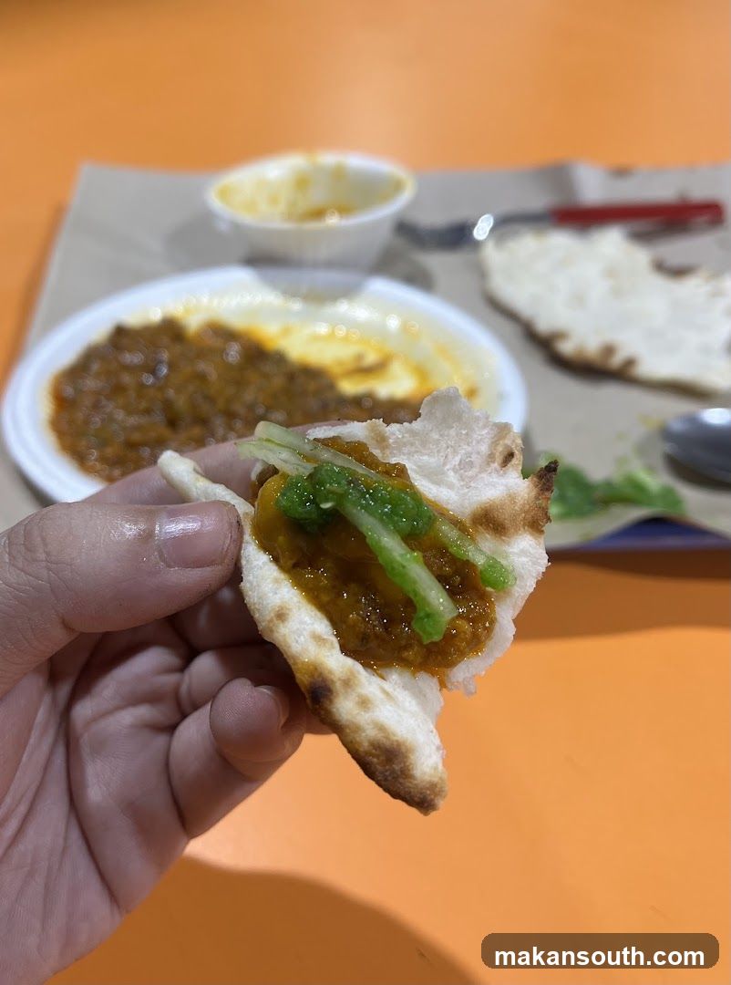 Hand holding naan with curry