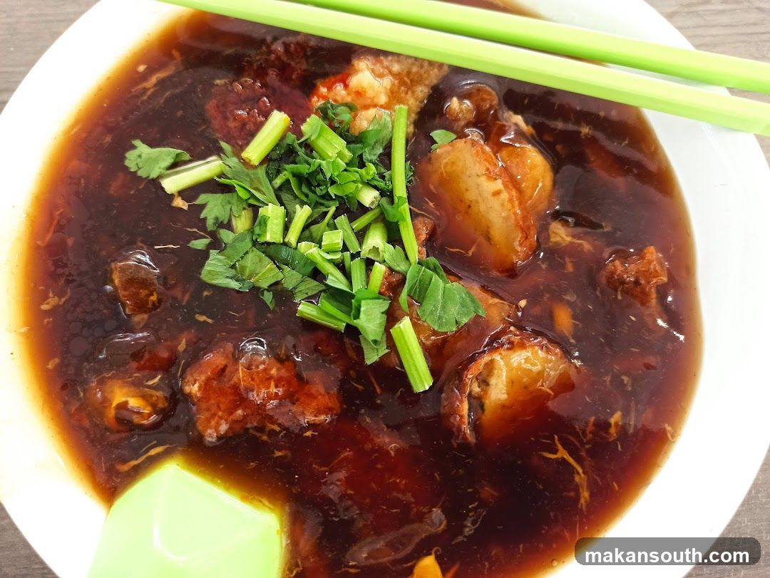 Bowl of Dark Broth with Meat and Herbs