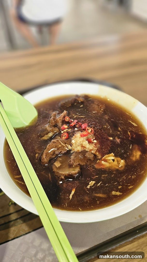 Bowl of Dark Broth with Meat and Chili