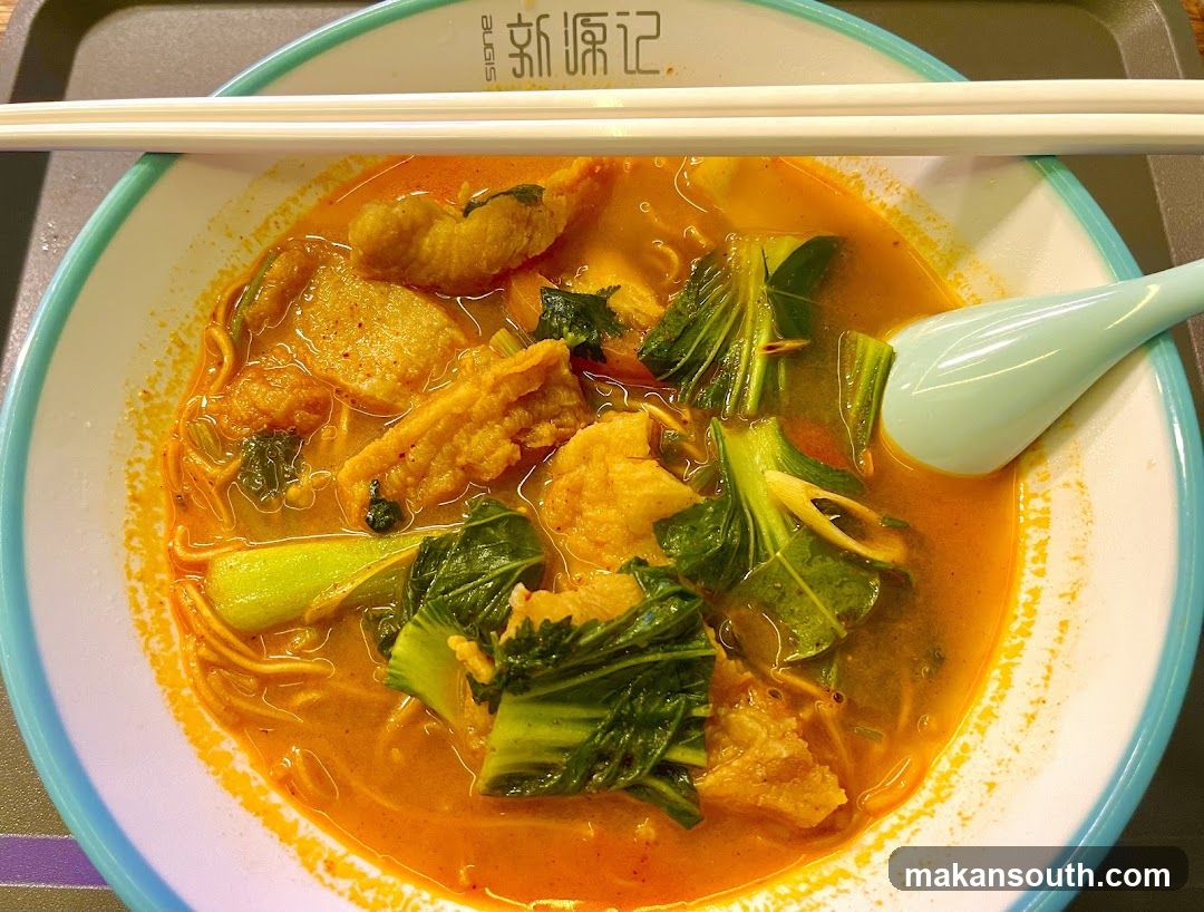 Bowl of spicy noodle soup with vegetables and tofu puffs