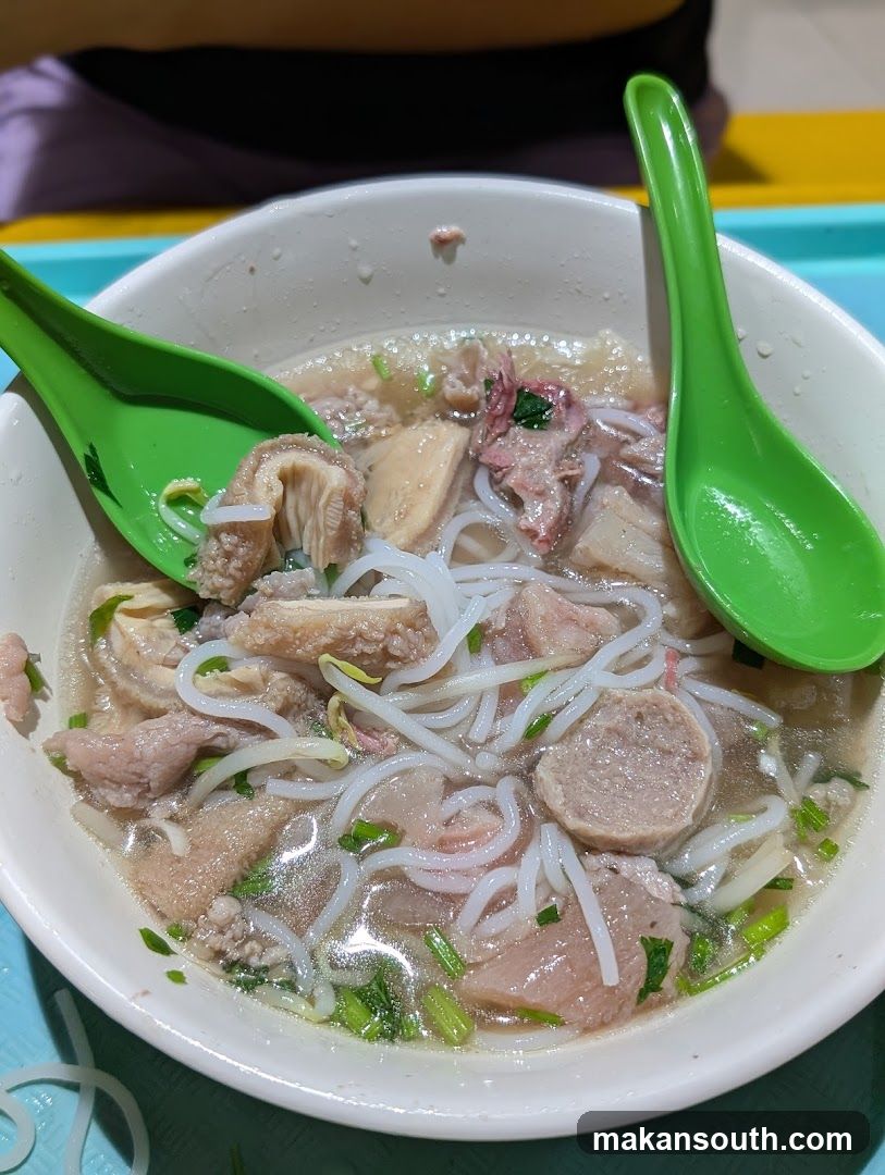 Bowl of Noodle Soup with Green Utensils