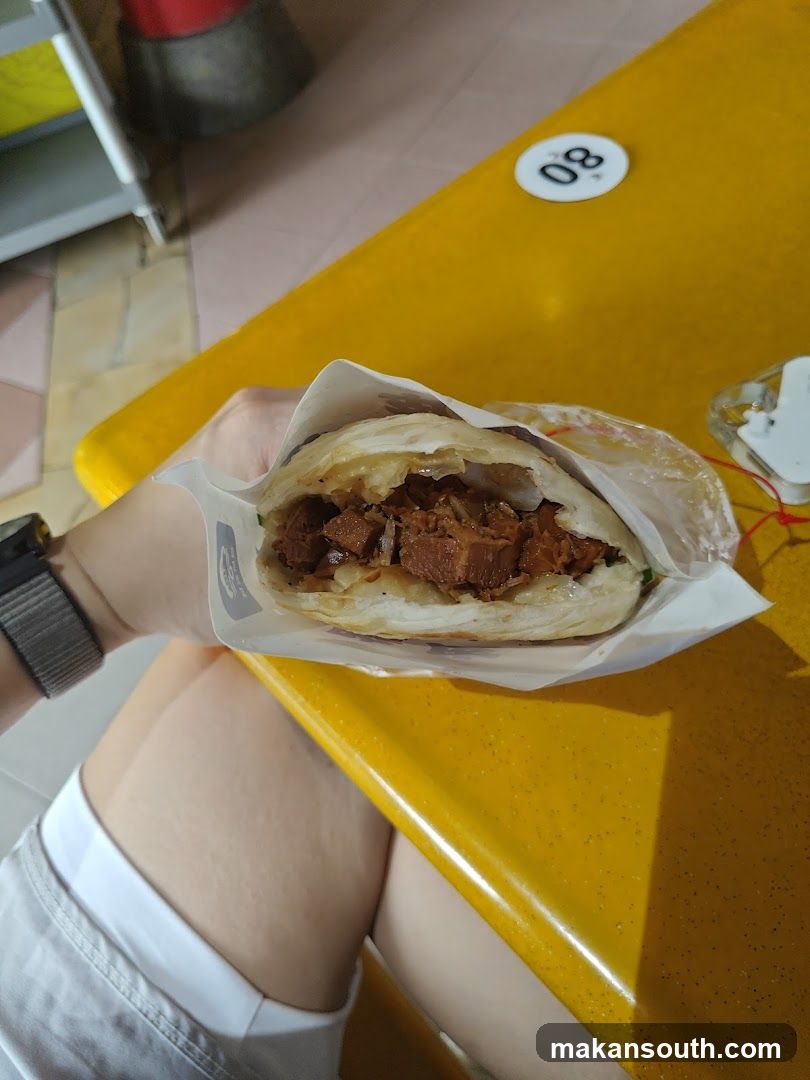 Hand holding a meat-filled bun at a yellow table