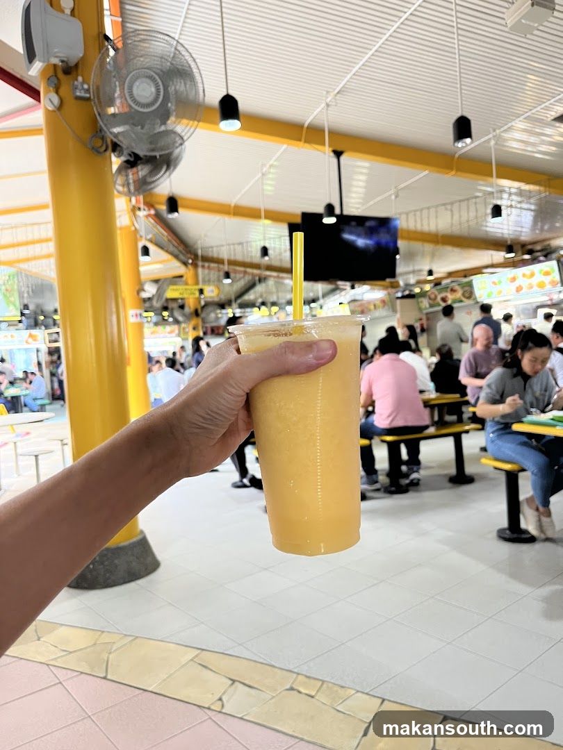 Hand holding yellow drink in food court
