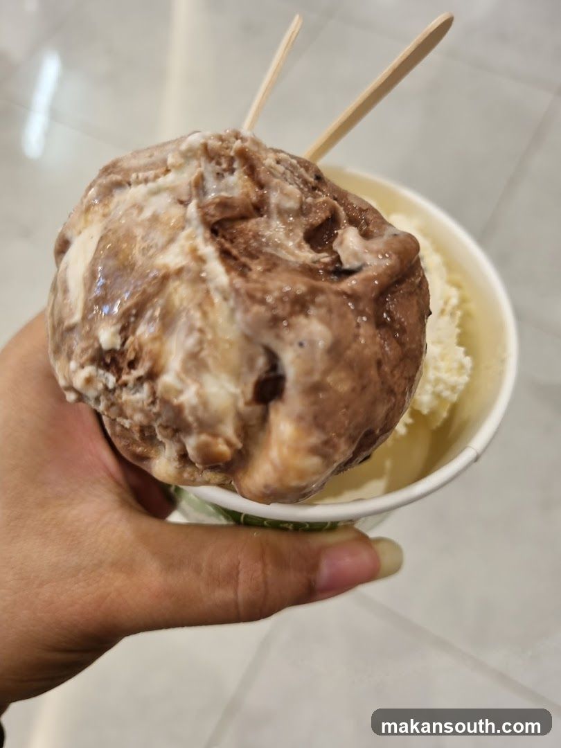 Hand holding ice cream cup with wooden sticks