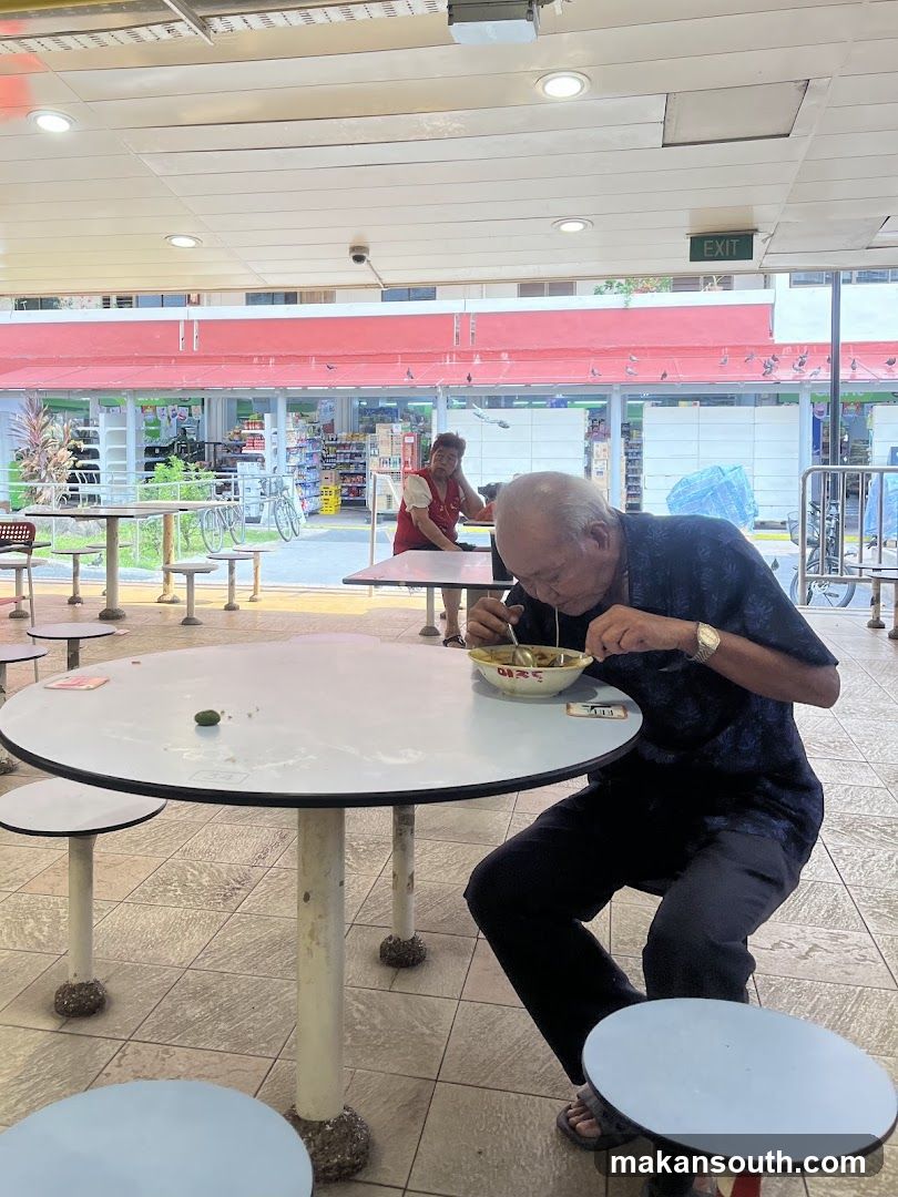 Elderly man eating at a food court table