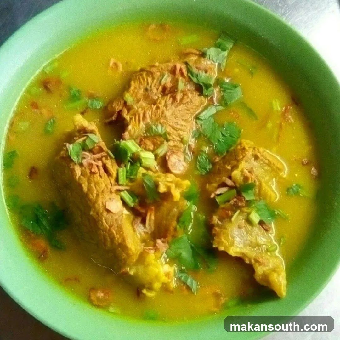 Bowl of Yellow Soup with Meat and Garnish