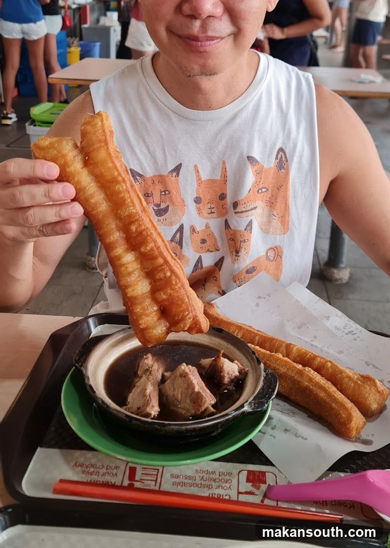 Person holding fried dough sticks with soup bowl