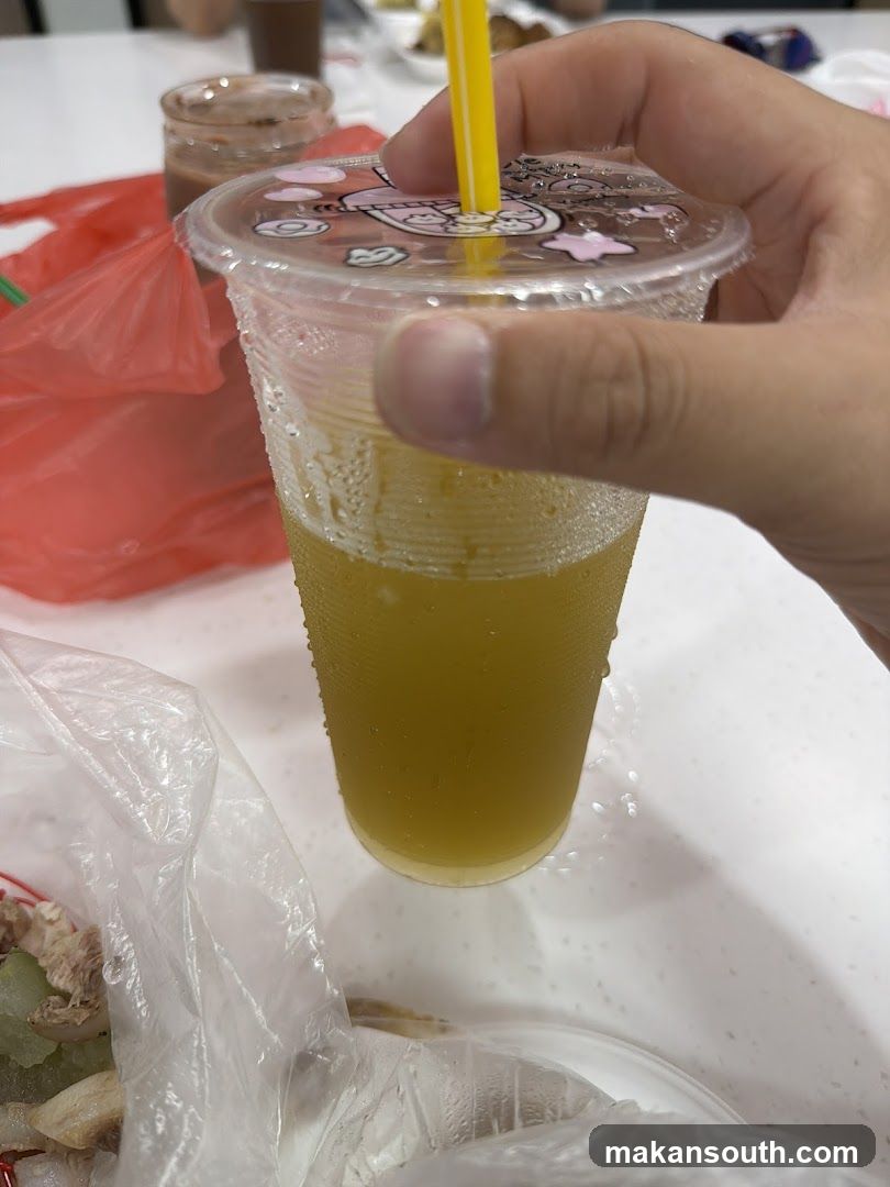 Hand holding a yellow drink with straw