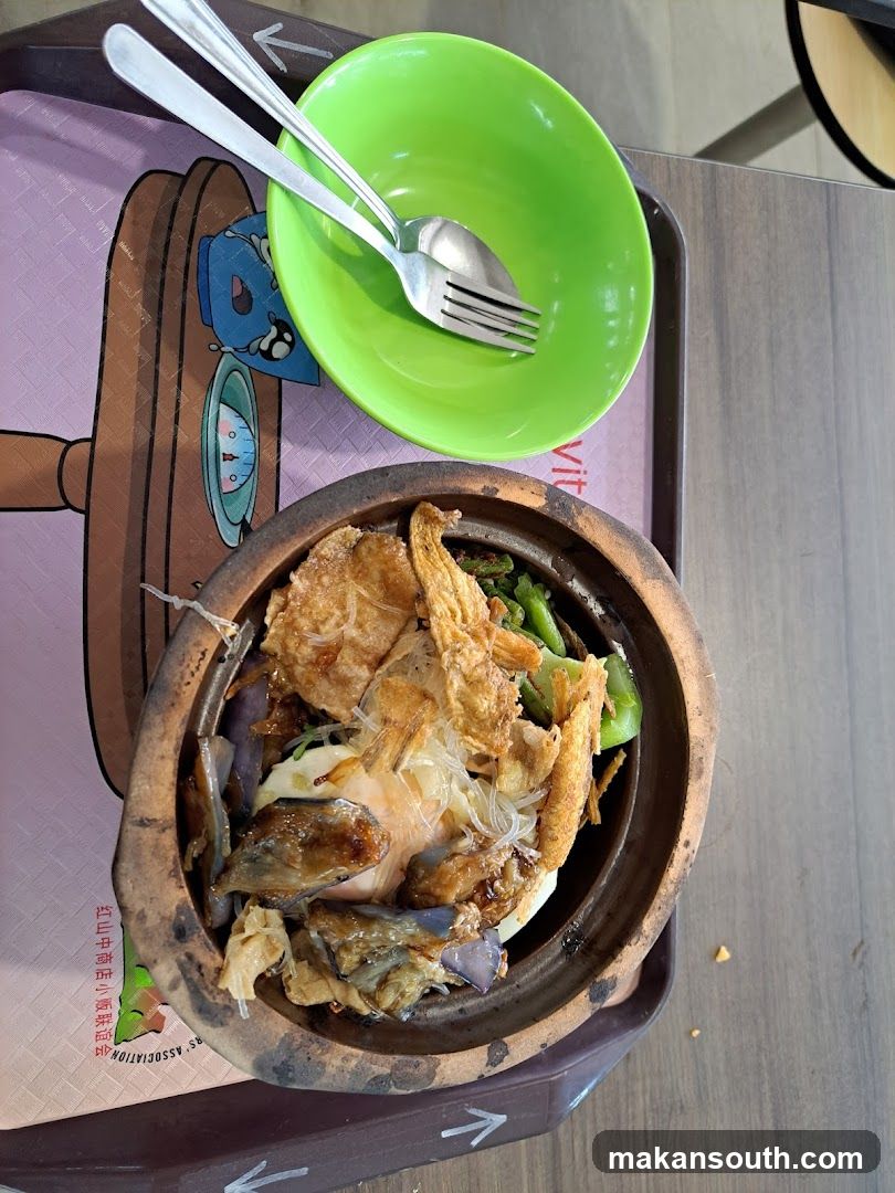 Claypot dish with green bowl and cutlery on tray