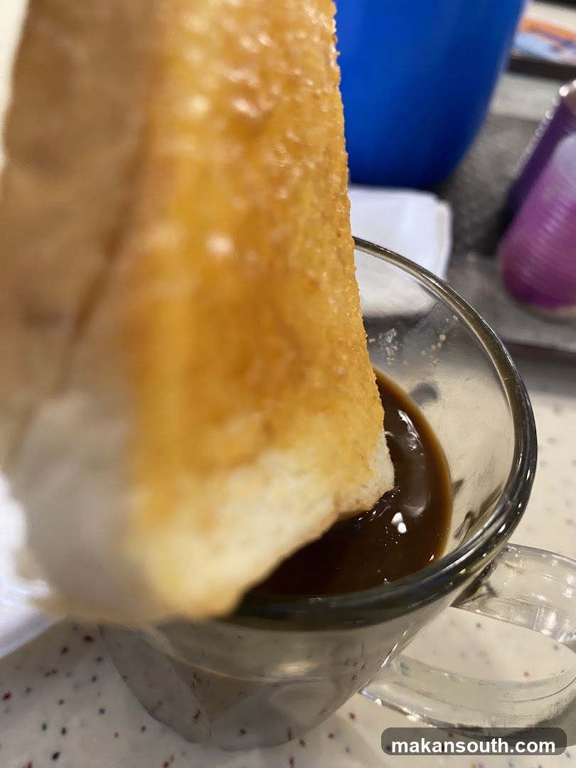 Close-up of toast dipping into coffee