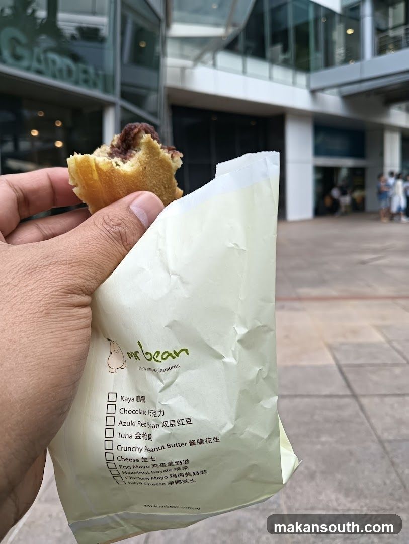 Hand holding food item with branded bag in urban setting