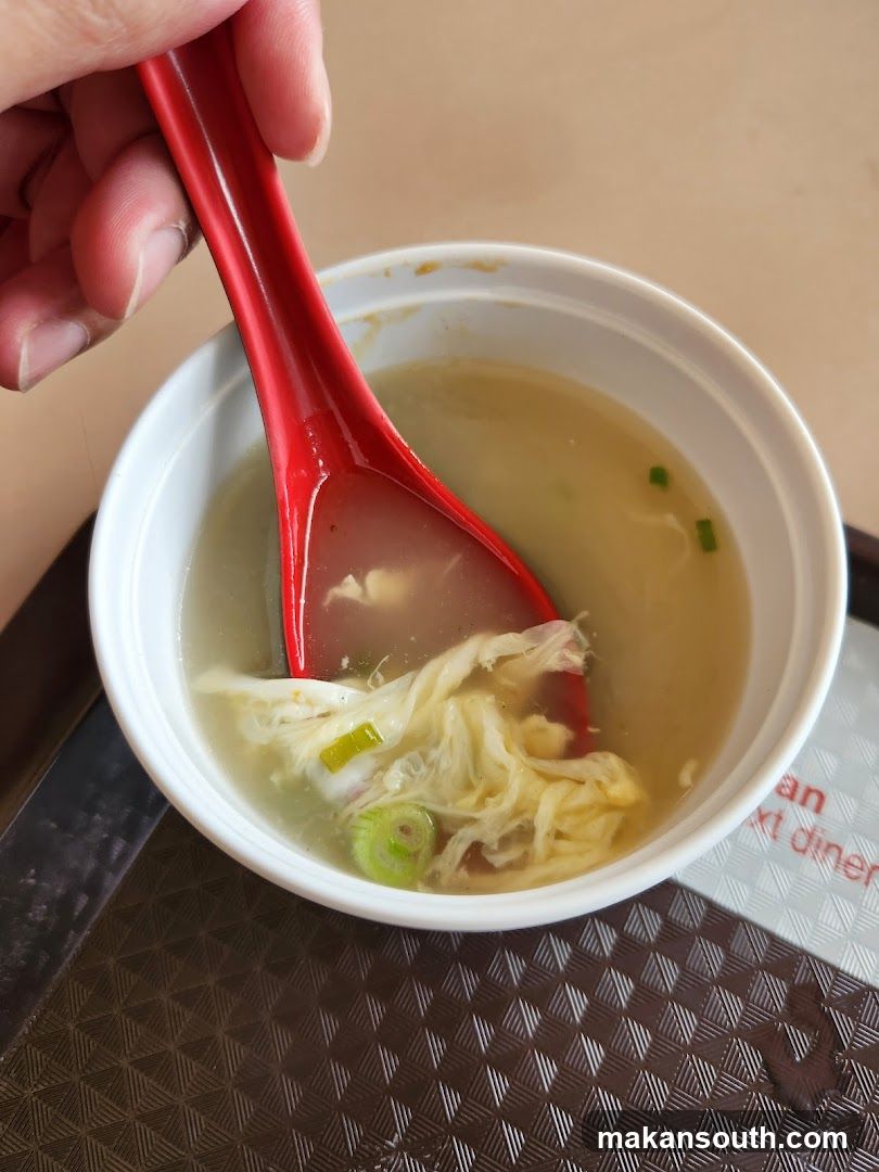 Bowl of Chicken Soup with Red Spoon