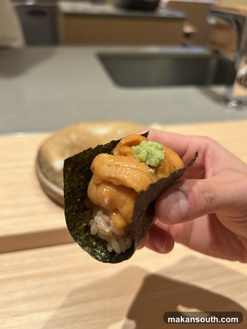 Hand holding sushi with uni topping