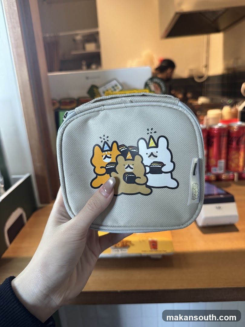 Hand holding a cute character pouch in a kitchen setting