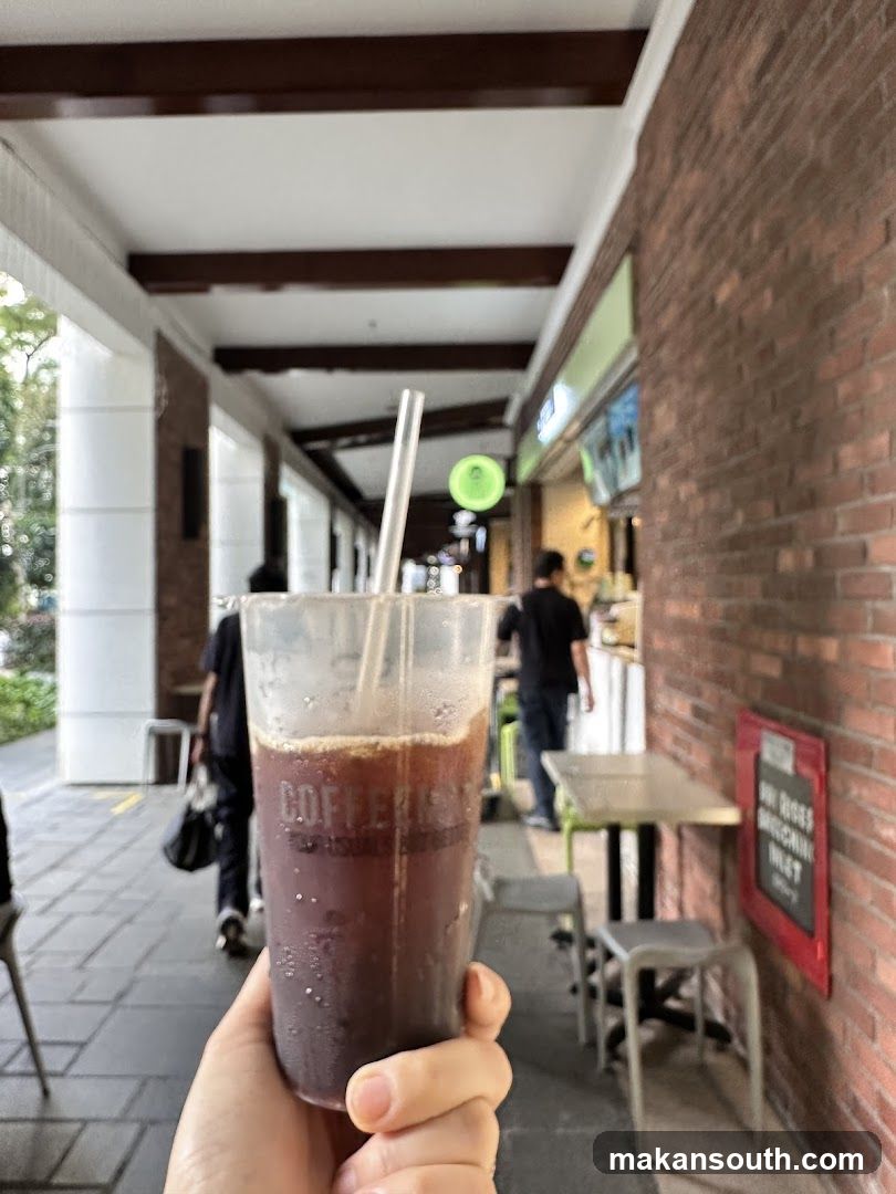 Hand holding iced coffee at outdoor cafe