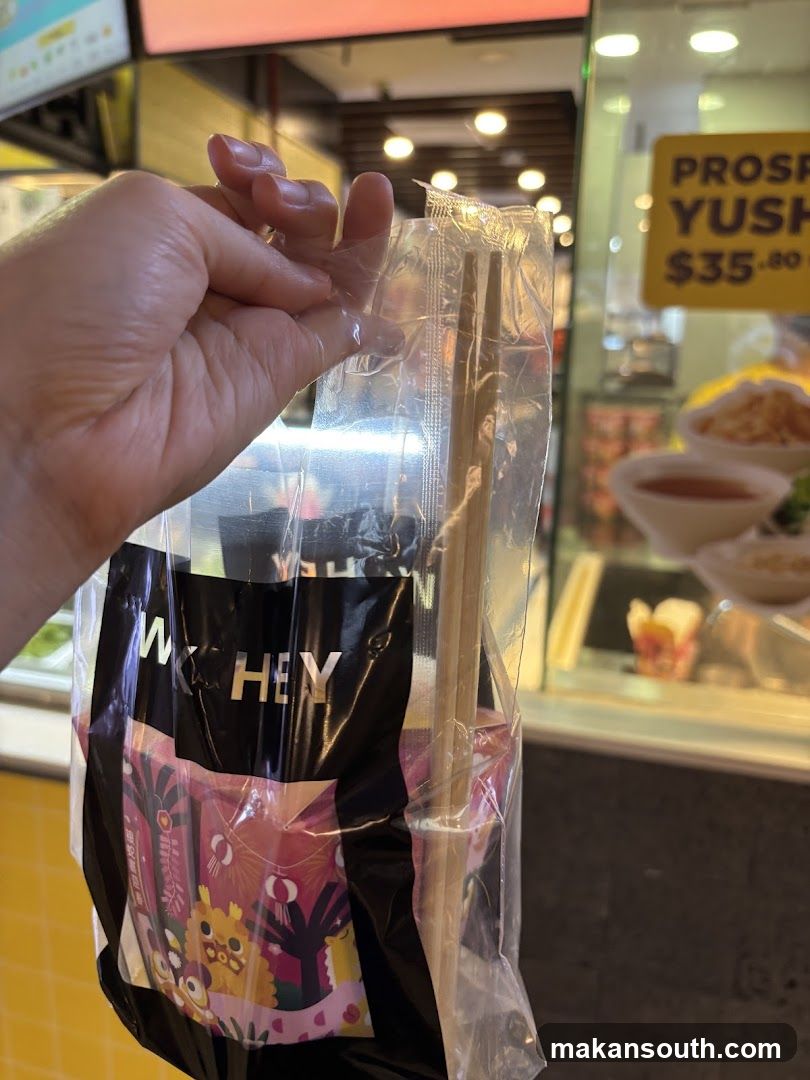 Hand holding packaged chopsticks near food stall
