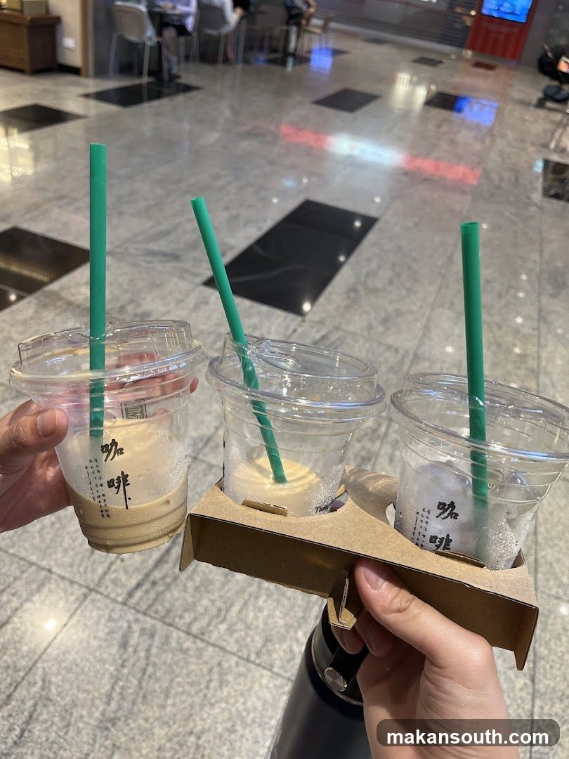 Three iced coffee drinks in cups with green straws