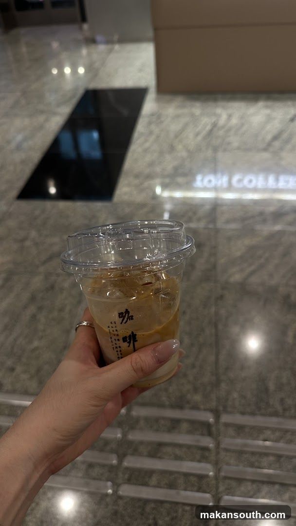 Hand holding iced coffee in a mall