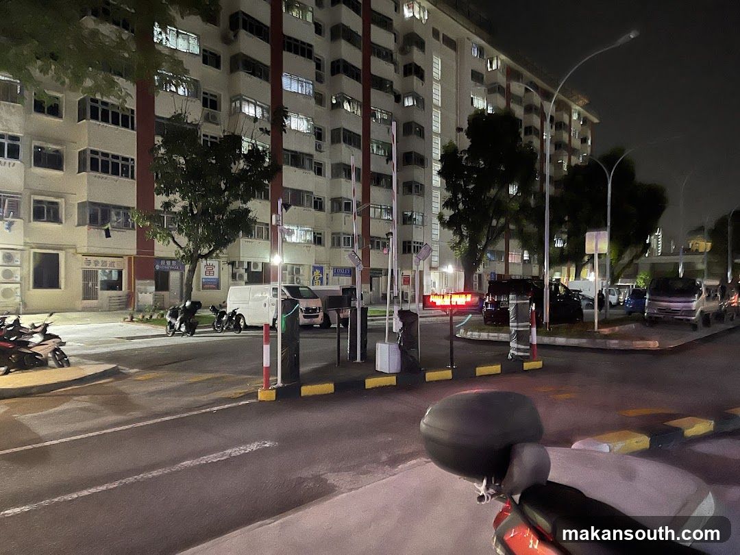 Night view of residential building entrance with parked vehicles and scooter in foreground