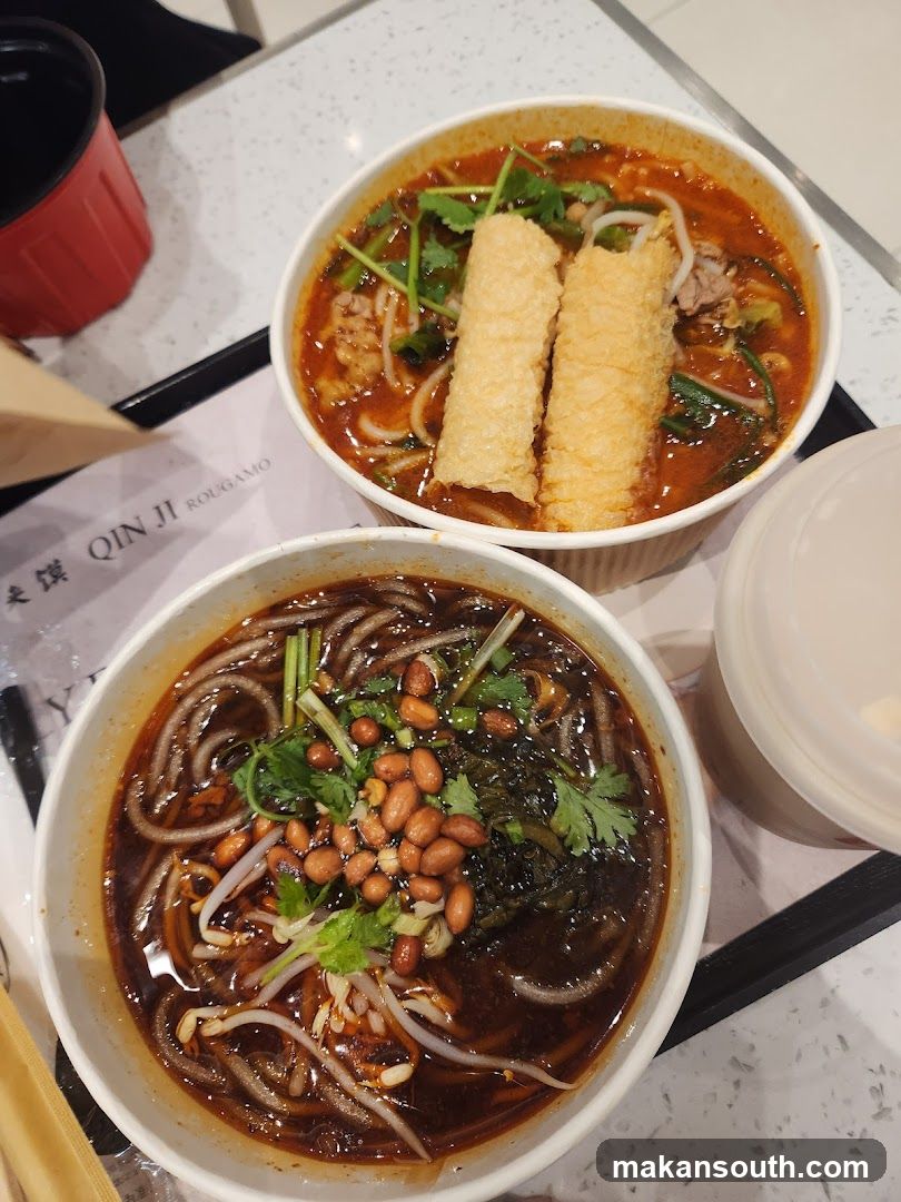Two bowls of spicy noodle soup with toppings