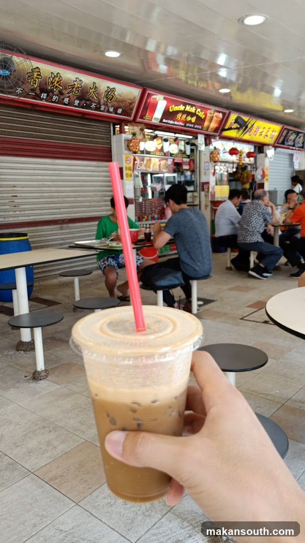 Hand holding iced coffee at food court