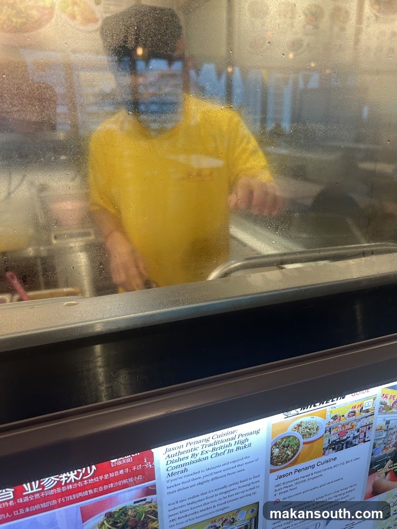 Chef in yellow uniform behind glass counter