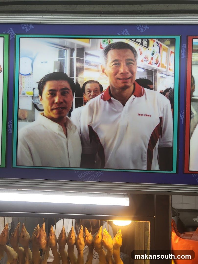 Food stall display with framed photo and hanging ducks