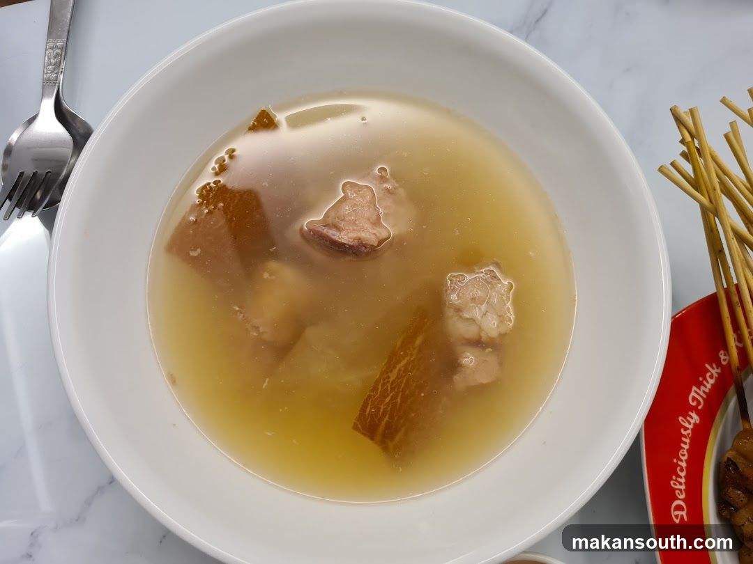 Bowl of clear soup with meat and skewers