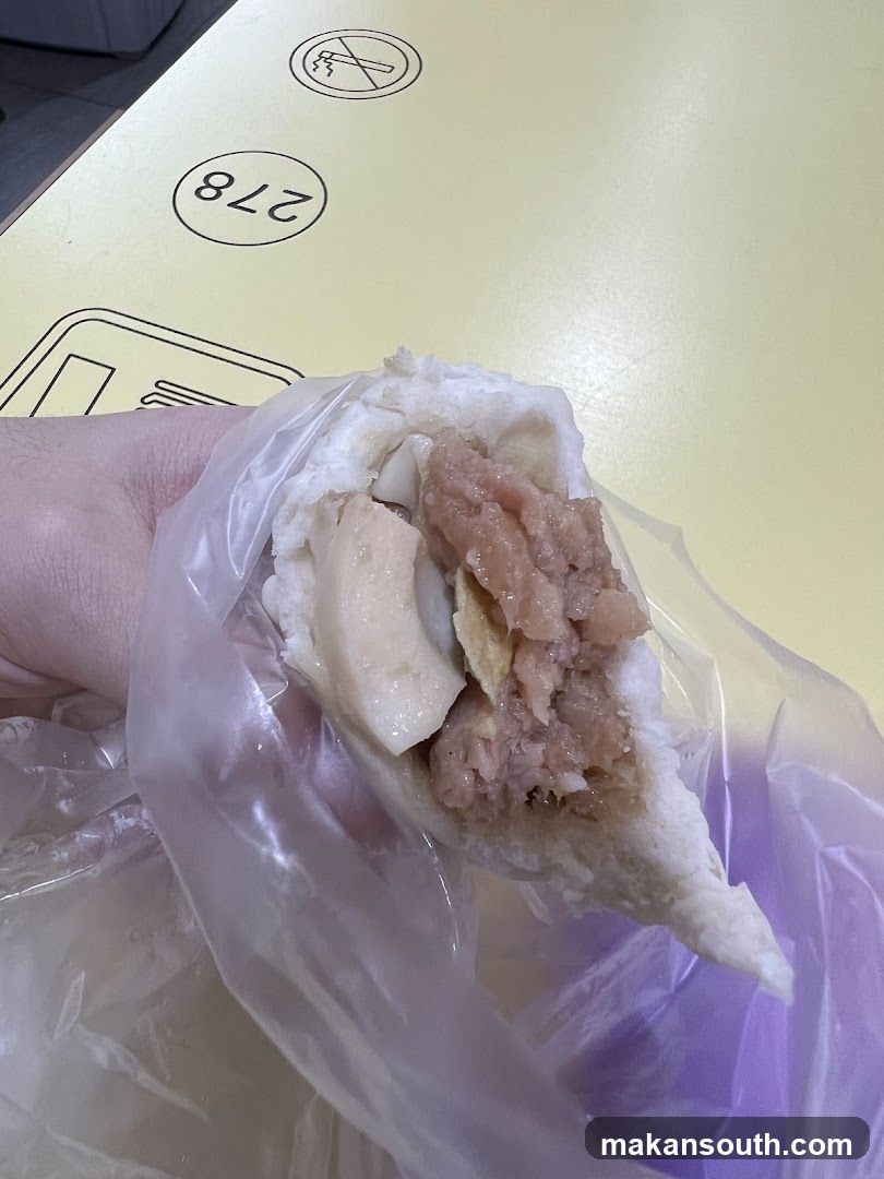 Hand holding a half-eaten bun with meat filling