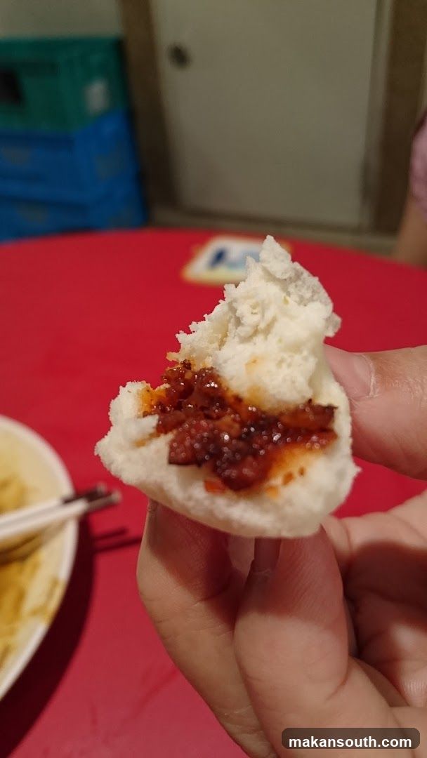 Hand holding a half-eaten bun with filling