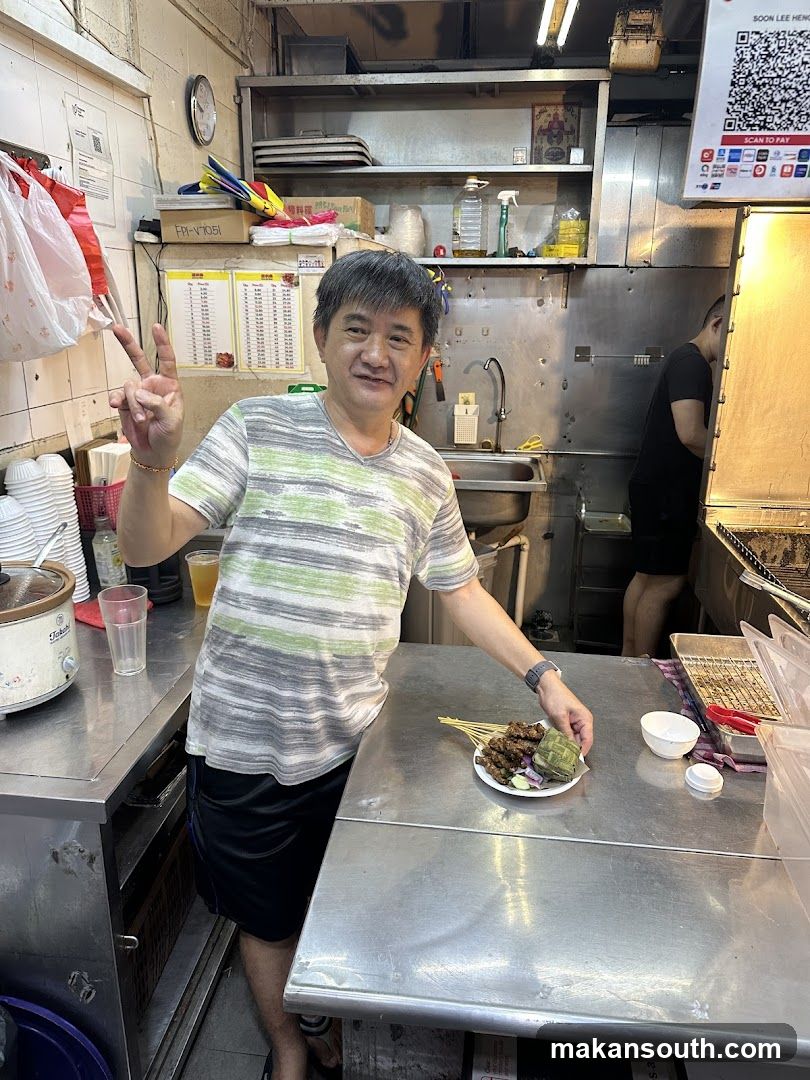 Man holding a plate of satay