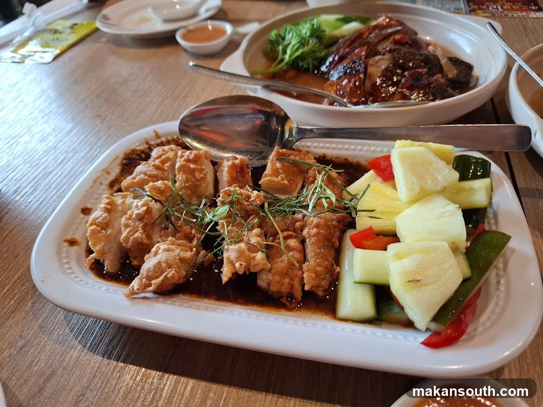 Slices of fried chicken with sauce and a side of pineapple and cucumber salad