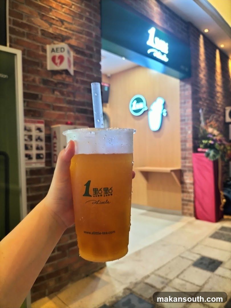 Hand holding a beverage in front of a shop