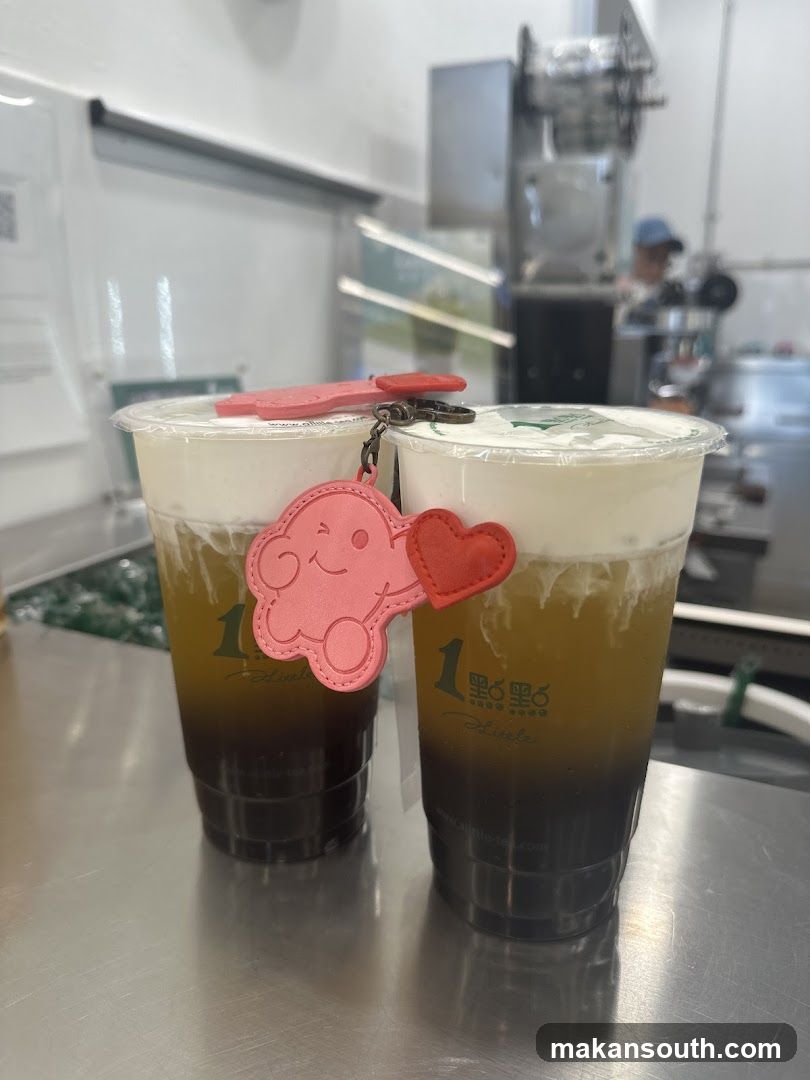 Two bubble tea drinks with a cloud charm