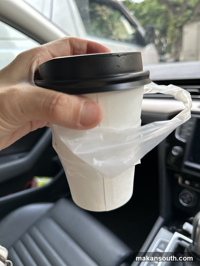 Hand holding a coffee cup in a car