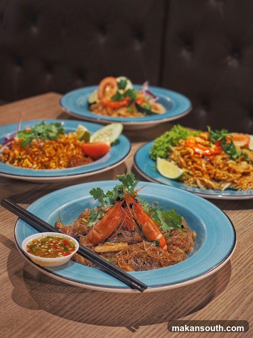 Four plates of Asian noodles and rice dishes