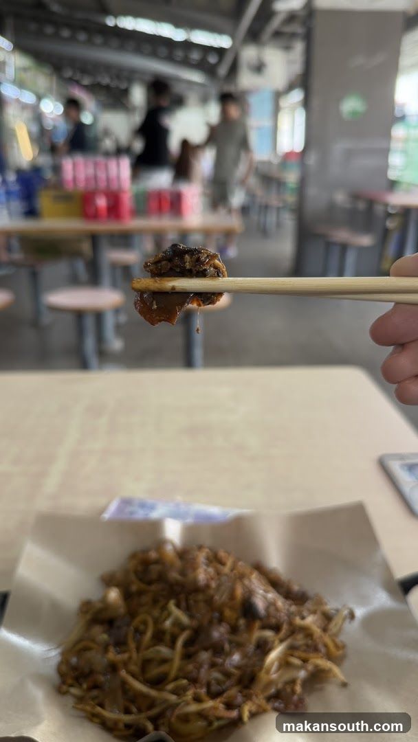 Chopsticks holding food over a plate of noodles