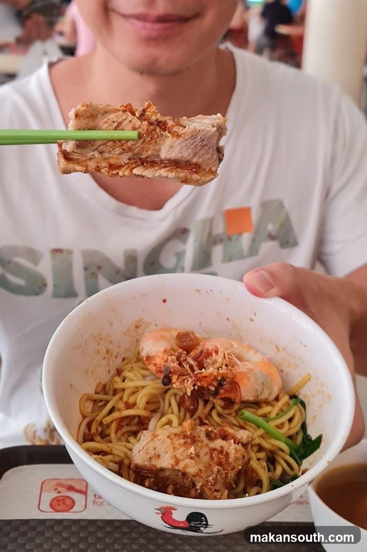 Person eating noodles with pork and shrimp