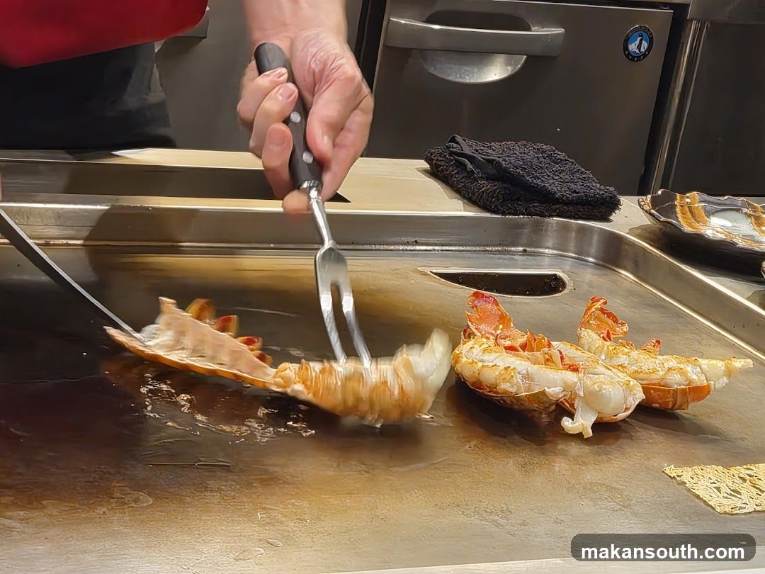 Chef cooking lobster tails on a flat-top grill