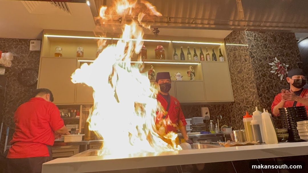 Chefs preparing food with a large flame