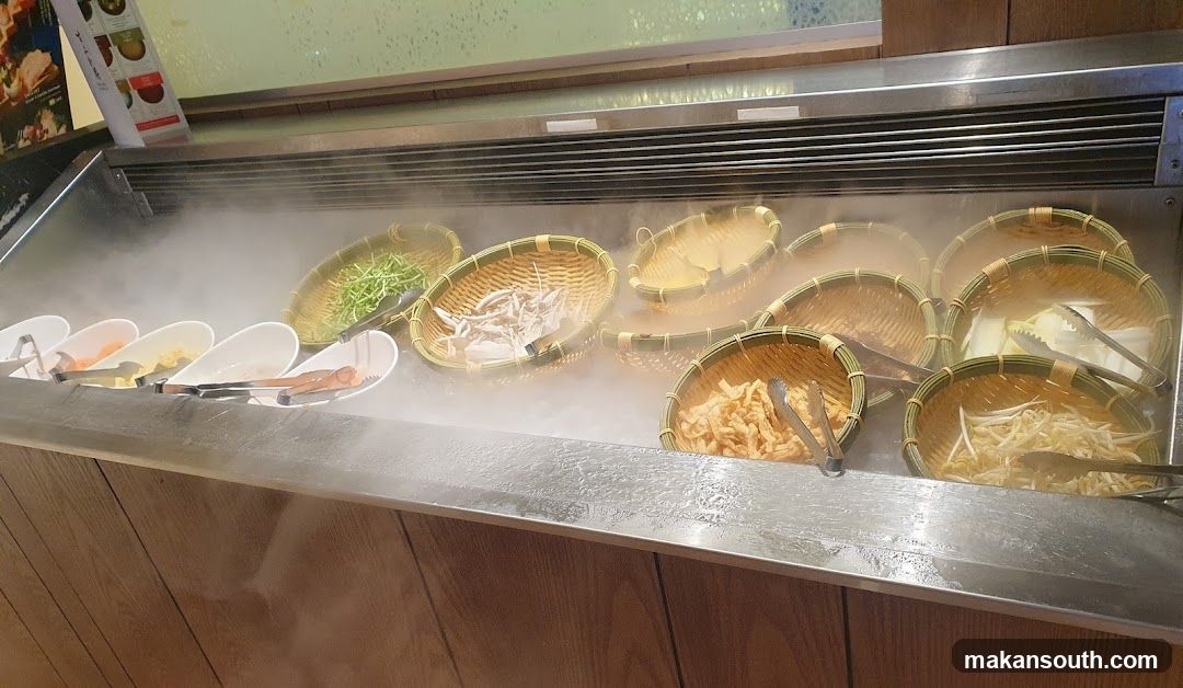 Buffet Display with Steaming Vegetables and Noodles