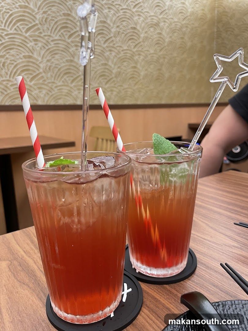 Two iced drinks with straws and garnishes
