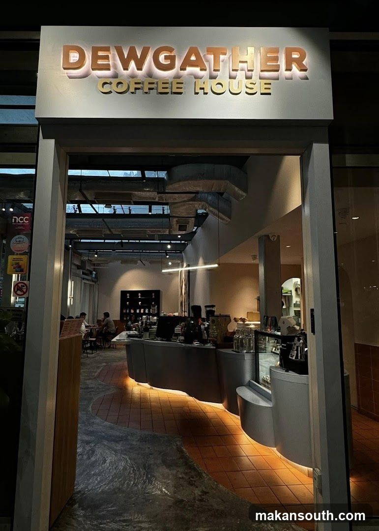 The entrance to Dewgather Coffee House is visible, with illuminated signage above the doorway. Inside, a modern interior with a curved counter, tiled flooring, and ambient lighting is seen. Several patrons are seated at tables in the background.