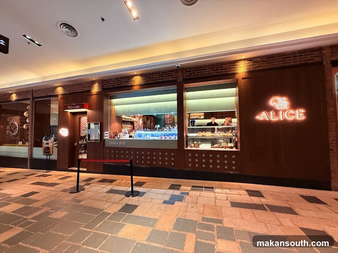 The exterior of a bakery and restaurant called Alice, featuring a prominent neon sign with a squirrel logo. The storefront has large windows displaying pastries and a coffee and drinks menu board. A "Welcome" sign is visible near the entrance.