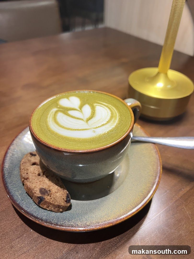Matcha latte with latte art and a cookie