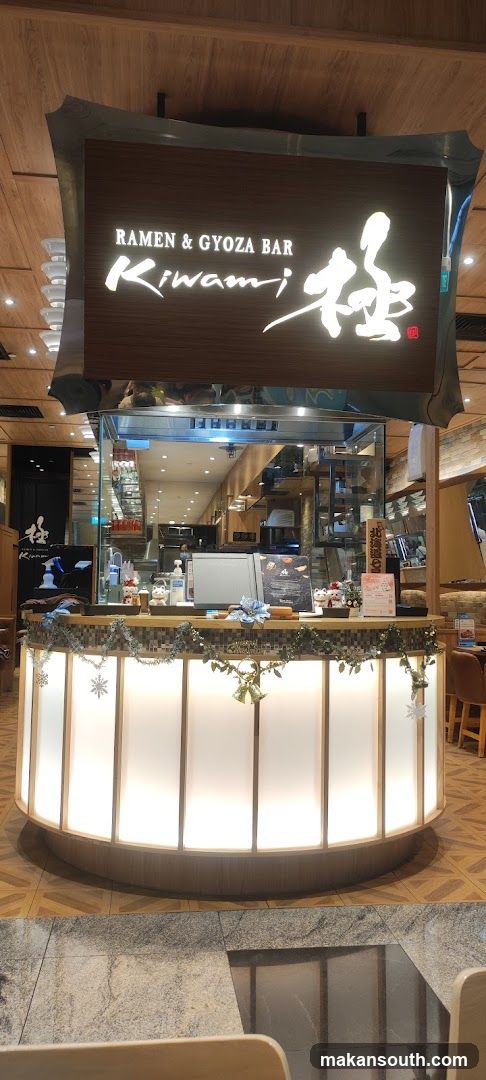 The exterior of a ramen and gyoza bar with a prominent illuminated sign that reads "RAMEN & GYOZA BAR Kiwami" in English and Japanese characters. The counter area is decorated with festive garlands and snowflakes.