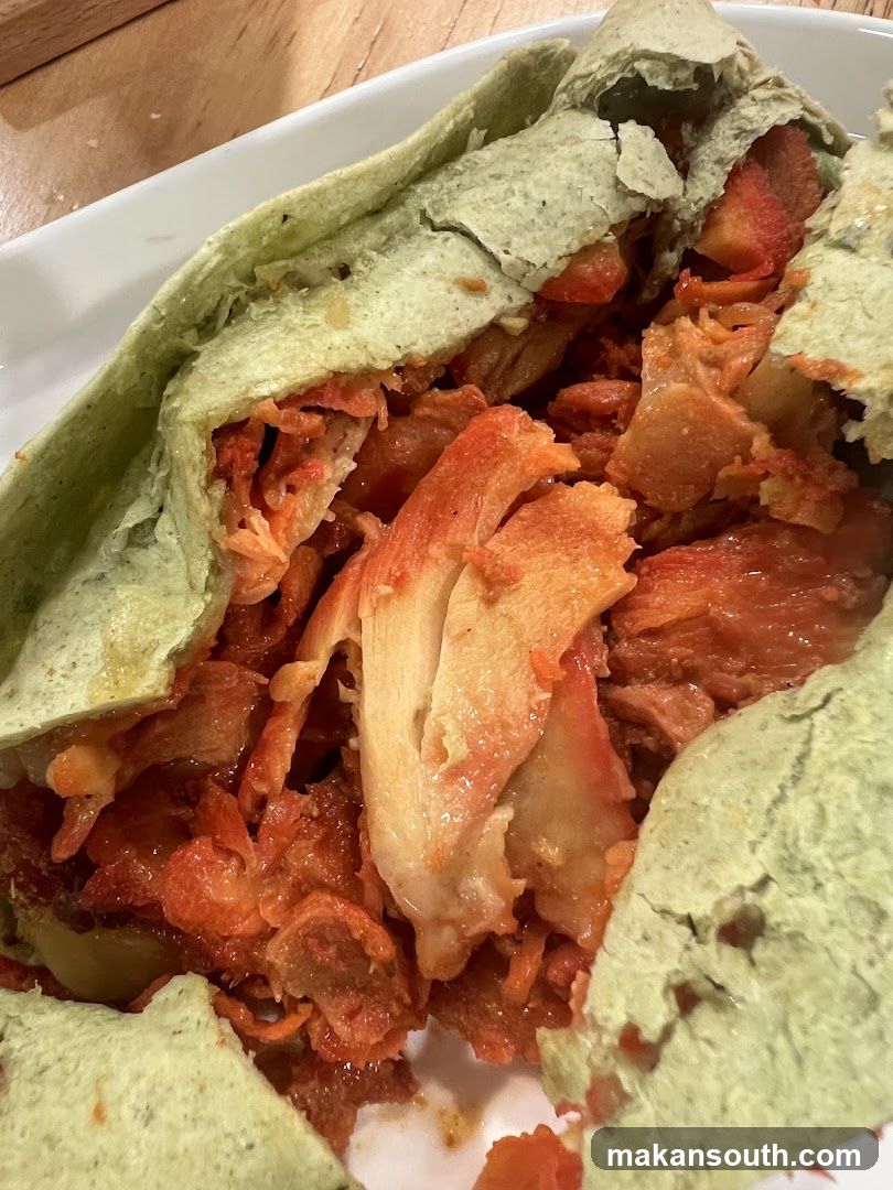Close-up of a green wrap filled with shredded meat and sauce