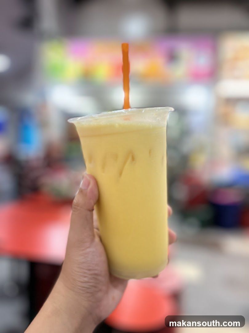 Hand holding a yellow drink with a straw